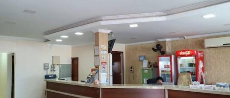 A reception area with a wooden counter, a Coca-Cola refrigerator, and a poster on the wall.