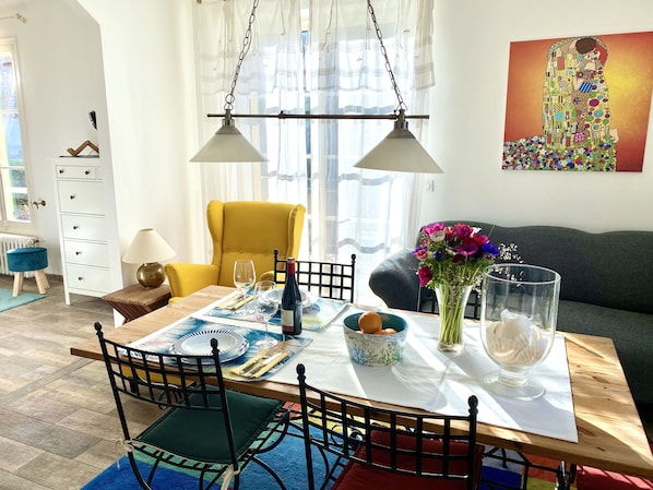 A dining area with a table set for two, a yellow armchair, and a sofa. - Fantastic Apartment Nuages in Villa Fontaine Vieille, Vence, near Nice (Vence)
