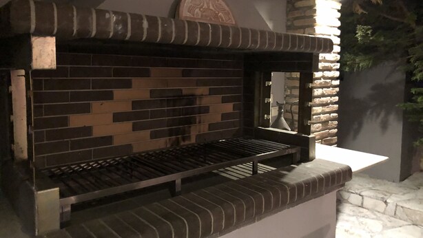 Un horno de ladrillo con una rejilla metálica y un fondo de pared de piedra.