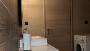 Un baño pequeño con lavamanos, inodoro y lavadora.
