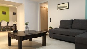 Una sala de estar moderna con una mesa de centro de madera oscura, un sofá gris y una pequeña planta en maceta.