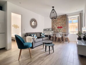 Una sala moderna con sofá, mesa de comedor y zona de cocina.