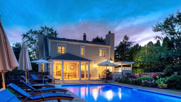Una casa con piscina, mobili da esterno e un patio.
