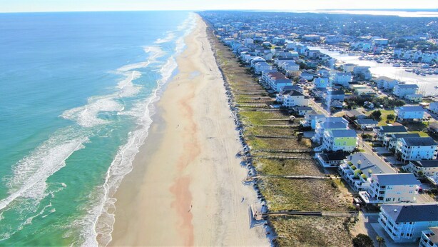Un quartier résidentiel situé sur la côte, avec des maisons le long de la plage et un port de plaisance.