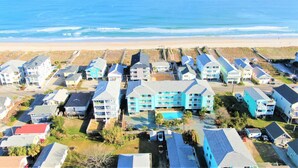 Un quartier résidentiel situé sur la côte, avec de nombreuses maisons à deux étages, une piscine et une plage en arrière-plan.