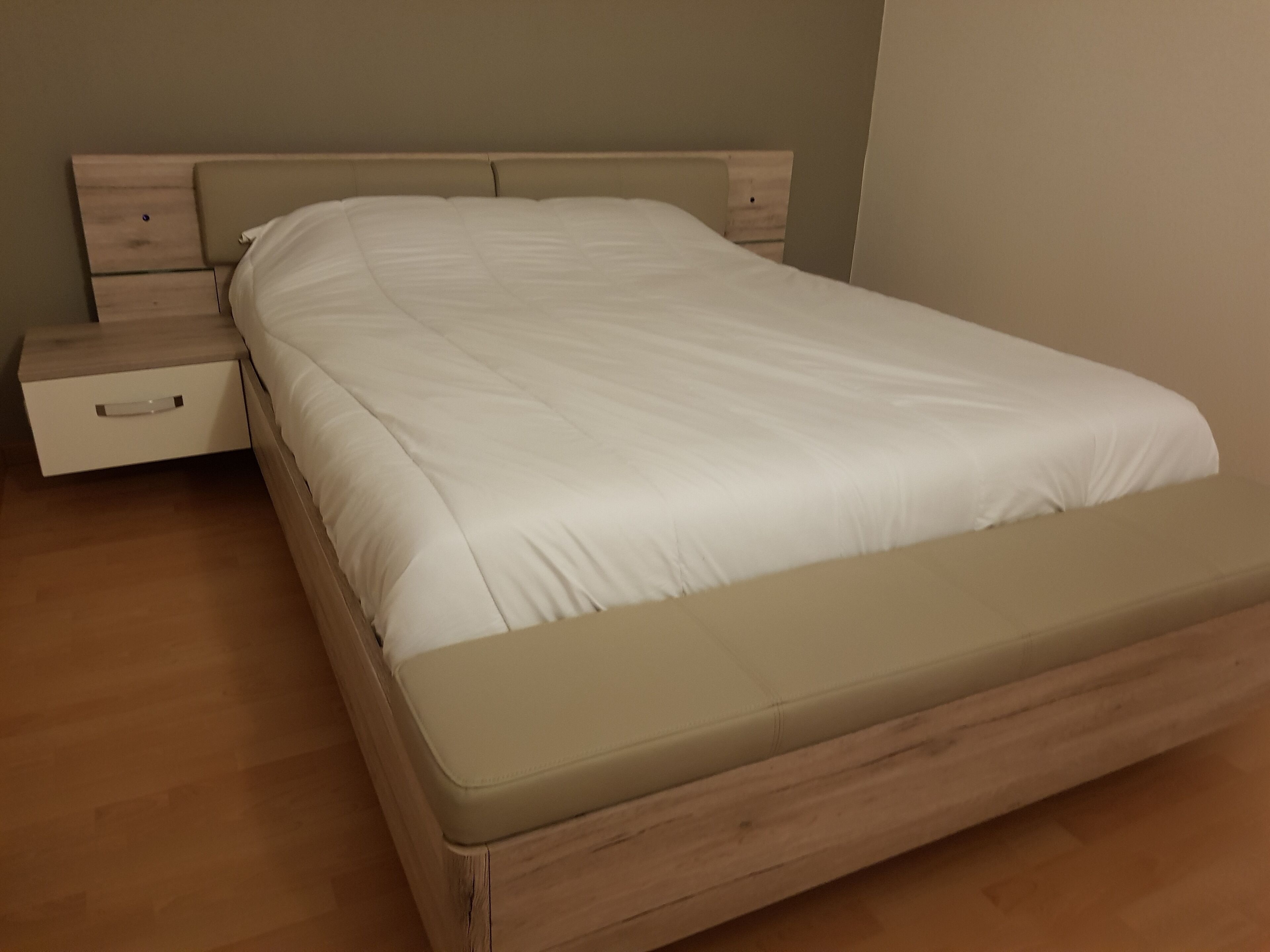 En säng med en träram och en beige madrass.