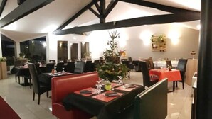 A restaurant with booths and tables, a Christmas tree, and a modern interior design. - Le Relais De Touvent (Boutenac-Touvent)