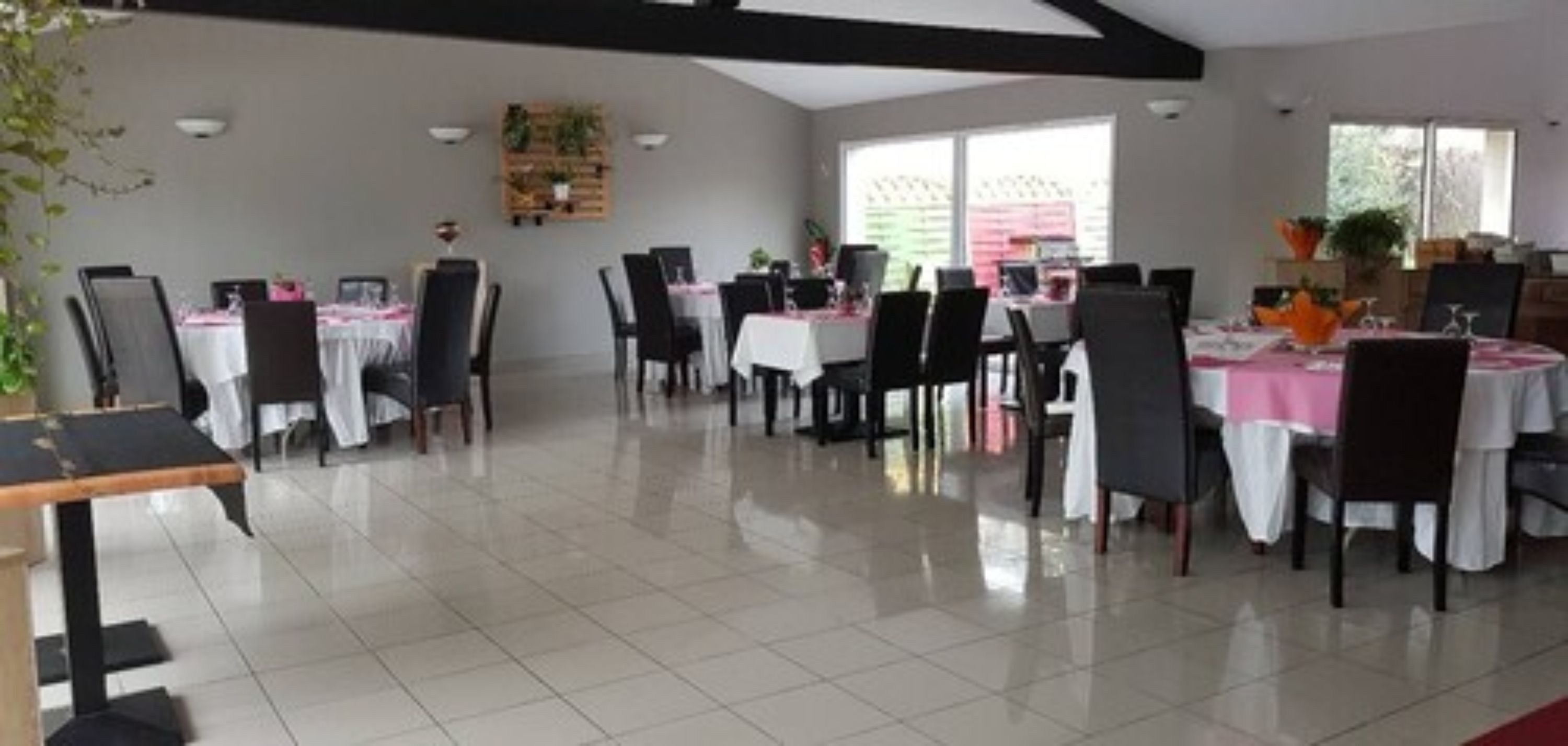 Un vaste espace dédié à la salle à manger, avec de nombreuses tables et chaises, de grandes fenêtres laissant entrer la lumière naturelle et un design moderne au niveau du plafond.