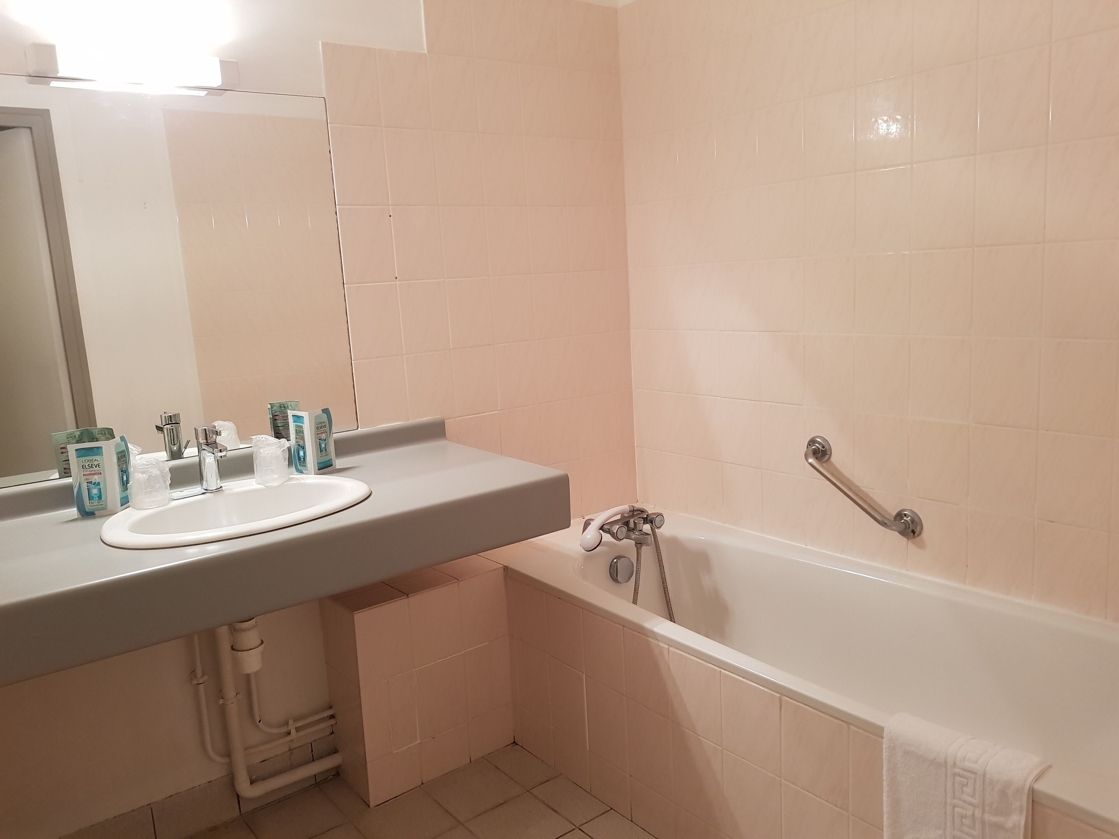 A bathroom with a white sink, mirror, and bathtub.