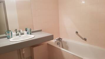 A bathroom with a white sink, mirror, and bathtub.