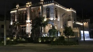 Un bâtiment historique à l’architecture riche et élaborée, doté de plusieurs tours et d’une façade bien éclairée.