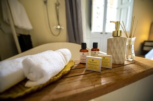 En træbakke med et hvidt håndklæde, to flasker Vervan-olier, en diffuser og en rørdiffuser på et hotelværelses bord.