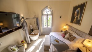 Une chambre à coucher moderne avec un grand lit, une coiffeuse, une baignoire et un téléviseur.