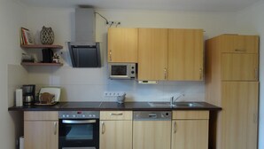 Une cuisine compacte avec des meubles en bois, un four à micro-ondes encastré, une machine à café et un lave-vaisselle.