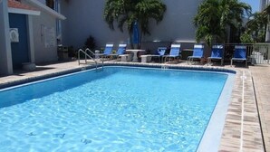 Ein Swimmingpool mit klarem, blauem Wasser, umgeben von Liegestühlen und Palmen.