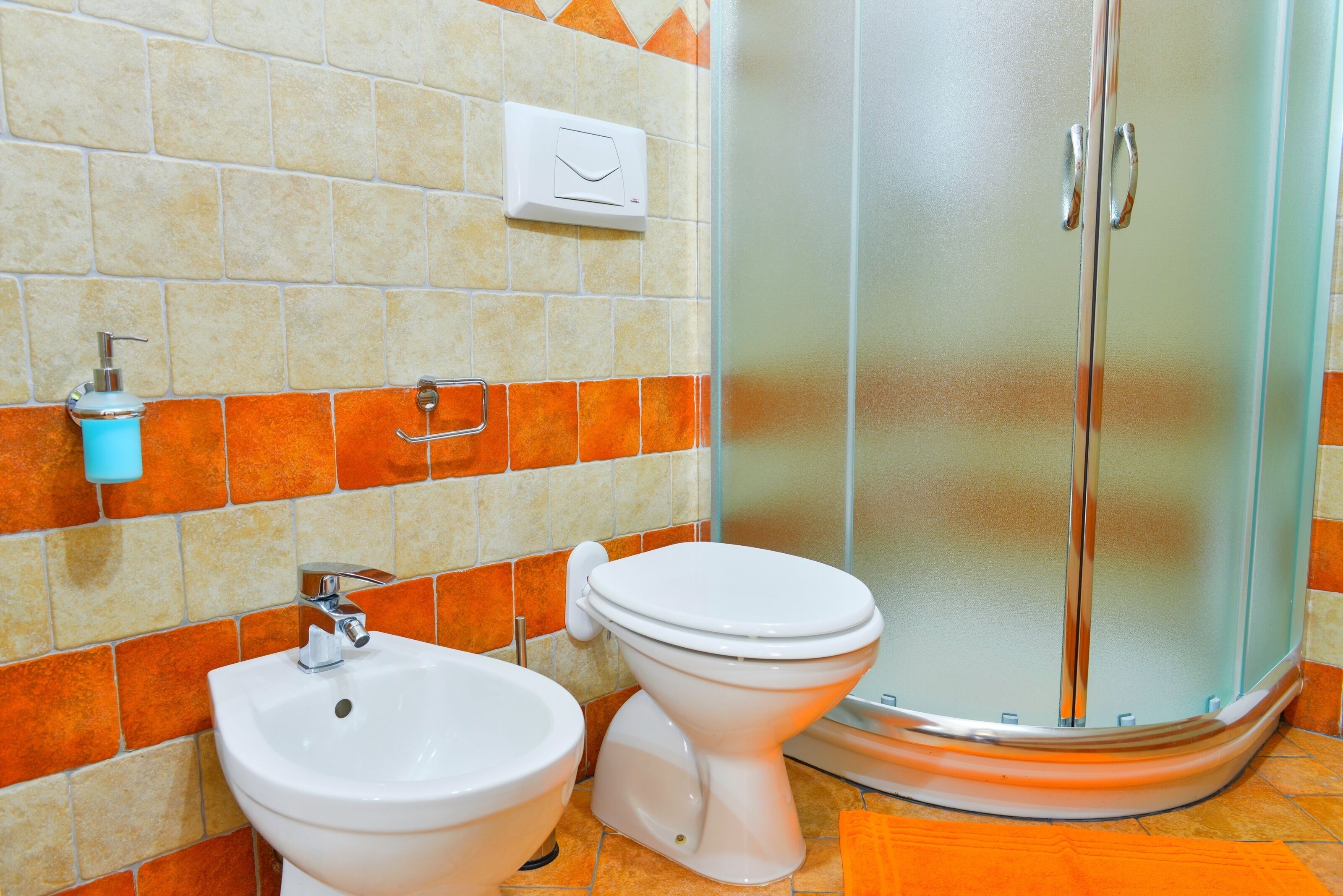 Une salle de bain équipée d’un bidet, de toilettes et d’une douche.