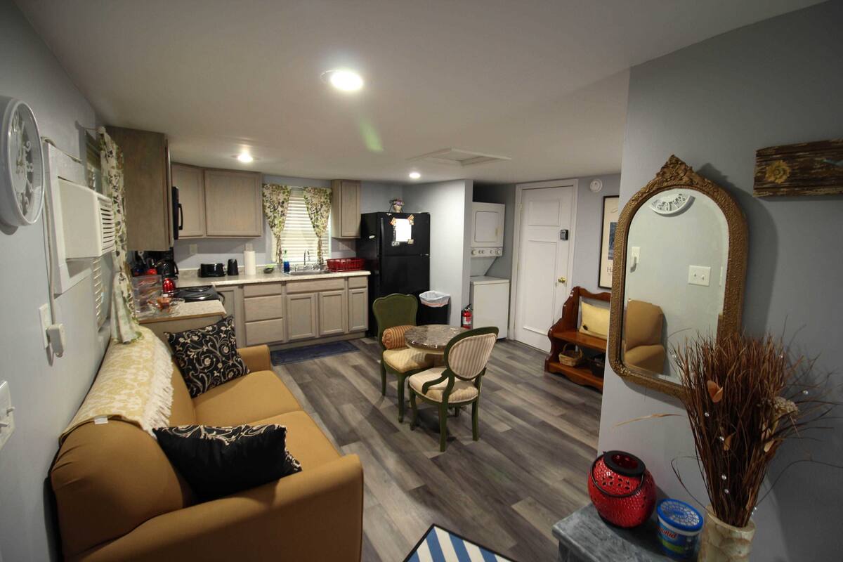 A compact living space with a kitchenette, a dining area, and a seating area with a sofa and chairs.