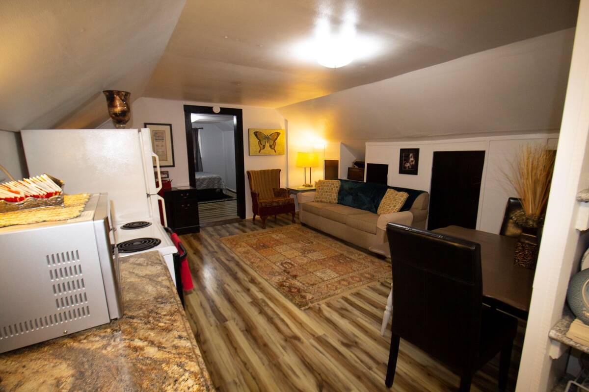 A compact living space with a kitchenette, a sofa, a dining table, and a lamp.