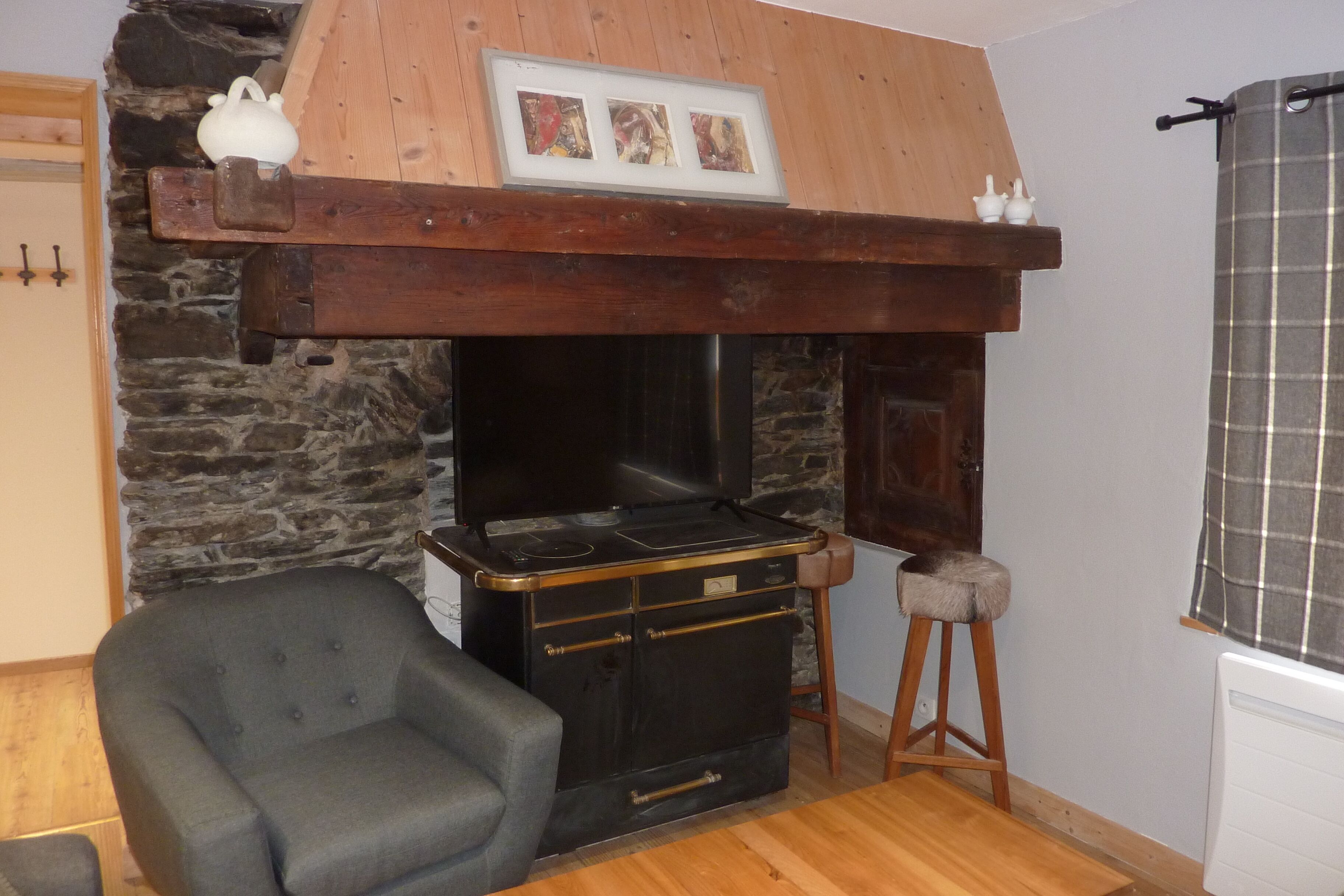 Una habitación acogedora con chimenea de piedra, repisa de madera y un sillón cómodo.
