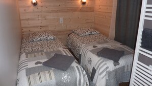 Una habitación con dos camas, cada una con ropa de cama y almohadas estampadas. Hay luces fijadas a la pared sobre las camas.