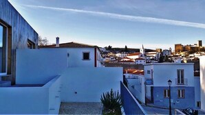 Zona residencial costera con edificios blancos modernos, cielo despejado y vista distante de un castillo histórico.