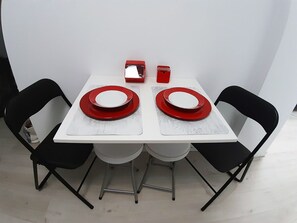 Une table à manger avec deux chaises, chacune ayant une assiette rouge et un petit objet rouge posé sur la table.