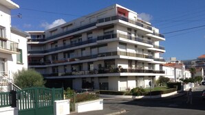 A multi-story residential building with balconies, a gated entrance, and a clear sky. - Apartment with balcony and terrace near the center and the beach (Royan)