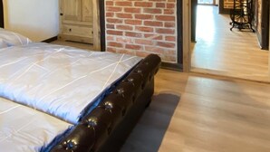 A bedroom with a large bed, wooden wardrobe, and a brick wall with a window. - Apartment in the Harz Mountains (Wernigerode)