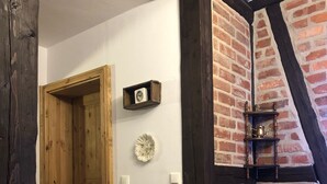 A hallway with a wooden door, a white wall, a brick wall, and a white radiator. - Apartment in the Harz Mountains (Wernigerode)
