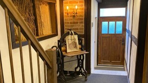 A hallway with a wooden staircase, a table with a bag, a brick wall, and a door with frosted glass panels. - Apartment in the Harz Mountains (Wernigerode)