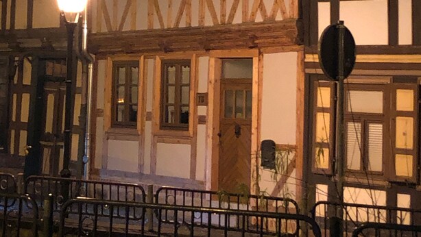 A traditional half-timbered building at night with illuminated windows and a street lamp. - Apartment in the Harz Mountains (Wernigerode)