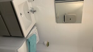 Een badkamer met een wit wastafel, een spiegel en een handdoekhouder.