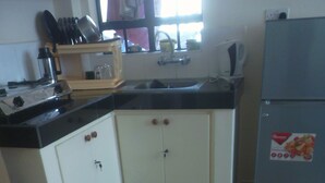 Een keuken met witte kasten, een zwart aanrecht en een koelkast.