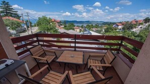 A balcony with wooden furniture, a table, and a view of a town and mountains.