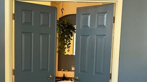 A bedroom with a bed, a chair, and a bathroom visible through an open door.