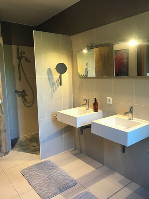 Ein modernes Badezimmer mit zwei Waschbecken, einer Dusche und einem Spiegel.