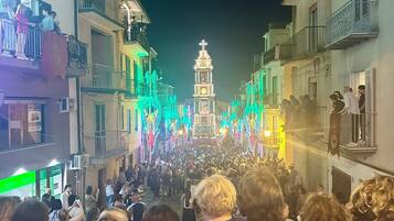 Rua movimentada com pessoas reunidas em volta de uma torre iluminada.