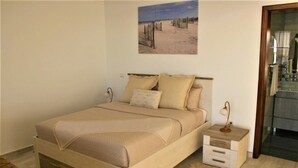 Een slaapkamer met een bed, nachtkastjes, een lamp en een schilderij aan de muur.
