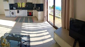 Een moderne keuken met een wasmachine, een eethoek met een glazen tafel, en een balkon met gordijnen.