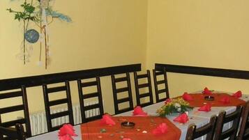 A dining area with a long table set for multiple guests, wooden chairs, and a decorative wall piece.