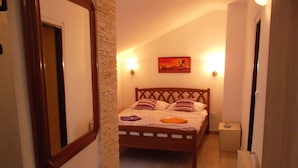 A bedroom with a wooden bed, a nightstand, a wall-mounted lamp, and a painting. - Hotel U Beránků (Libochovice)