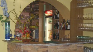 A bar area with a stone counter, shelves with bottles and glasses, and a Coca-Cola sign. - Hotel U Beránků (Libochovice)