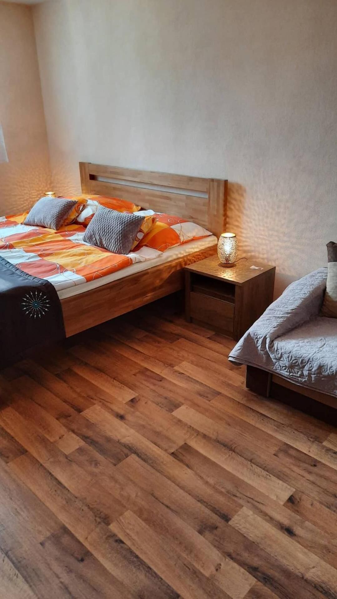 Quarto com duas camas, mesa de cabeceira, criadeira e uma cadeira.