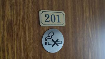 A wooden surface with a sign labeled '201' and a circular sign with a smoking symbol and a crossed-out cigarette.