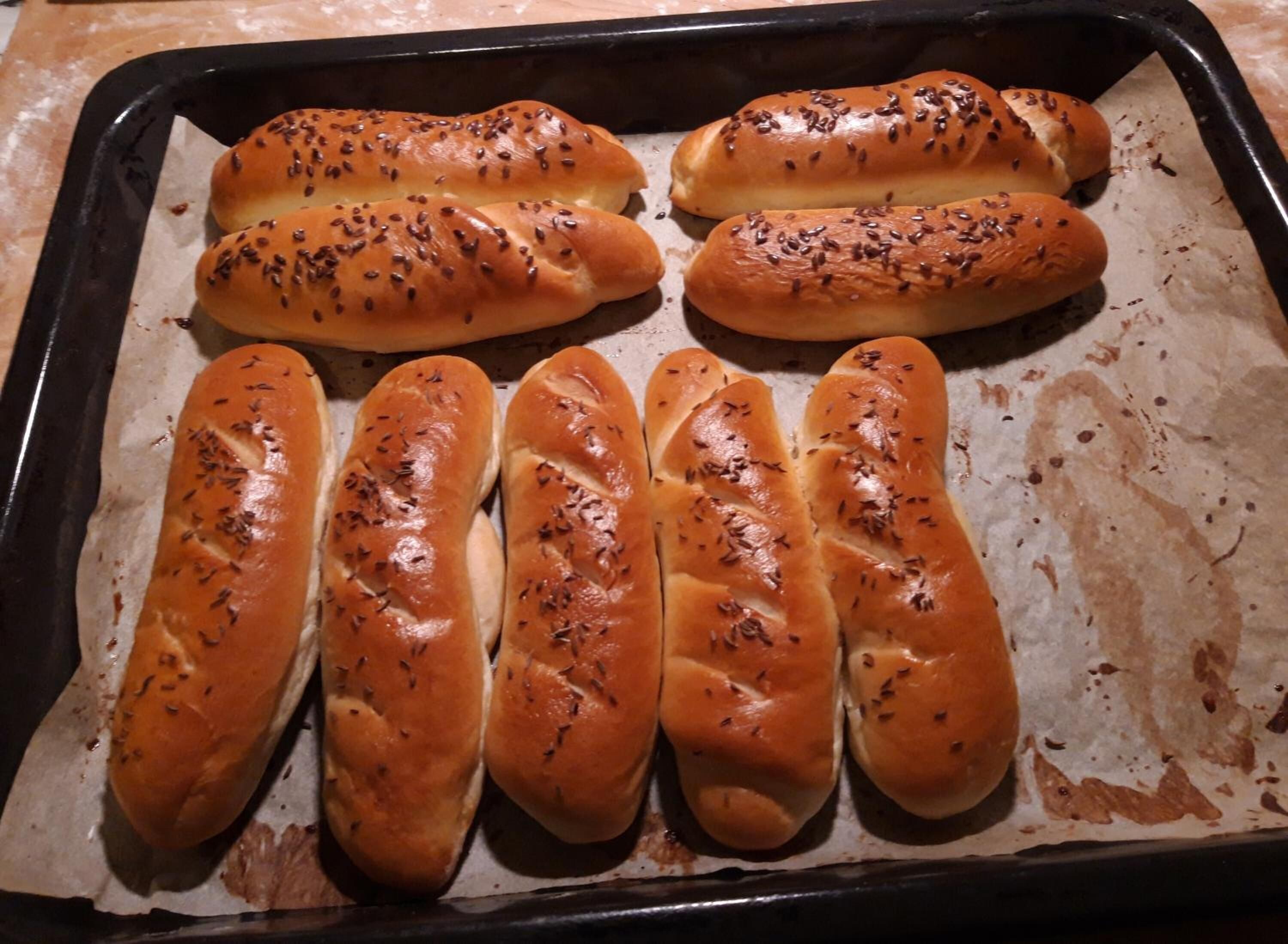 A baking tray with six loaves of bread, each topped with seeds.