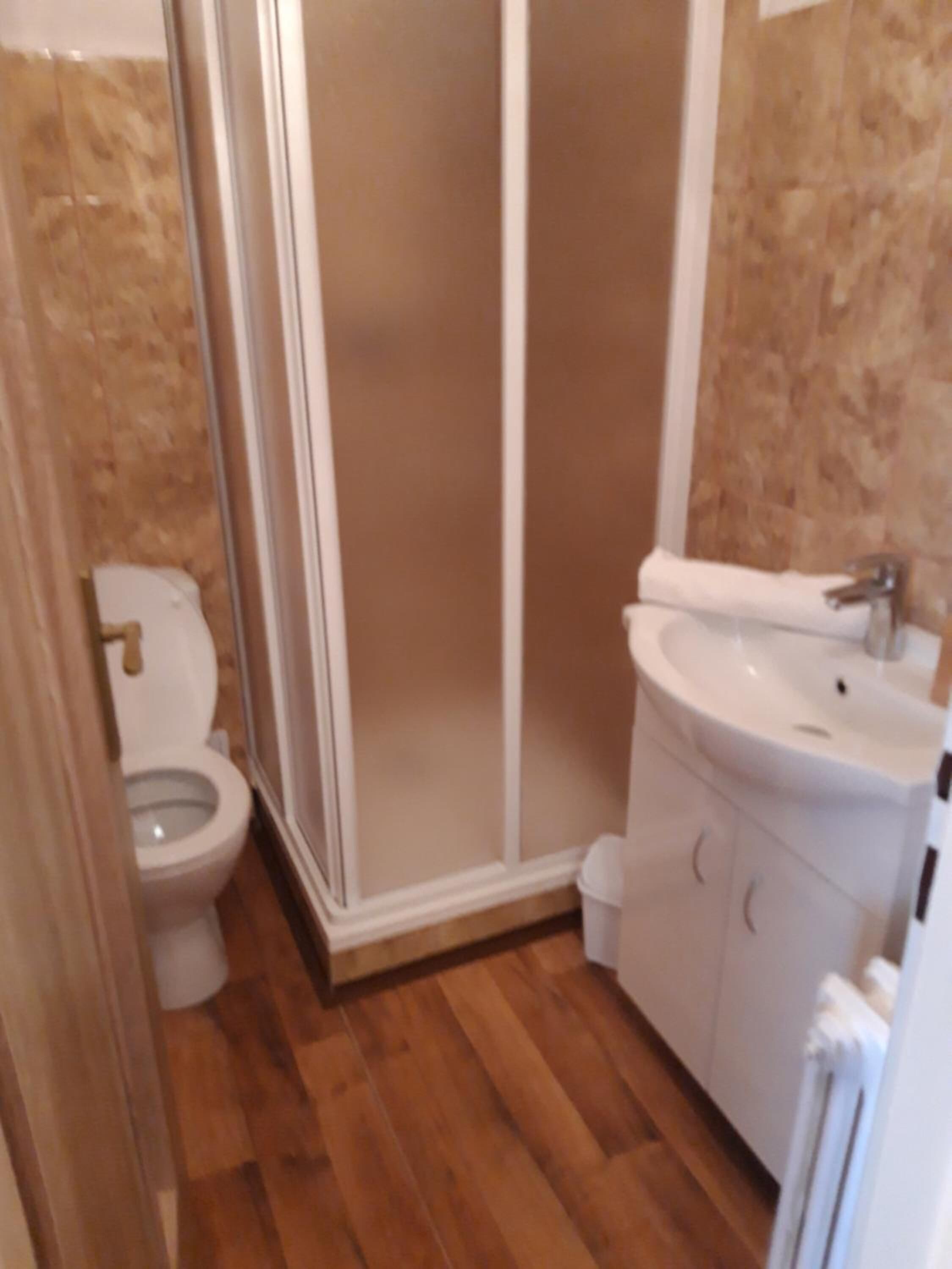 A small bathroom with a toilet, a shower enclosure, and a sink.