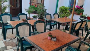 An outdoor seating area with tables and chairs, potted plants, and a large umbrella. - Hotel U Beránků (Libochovice)