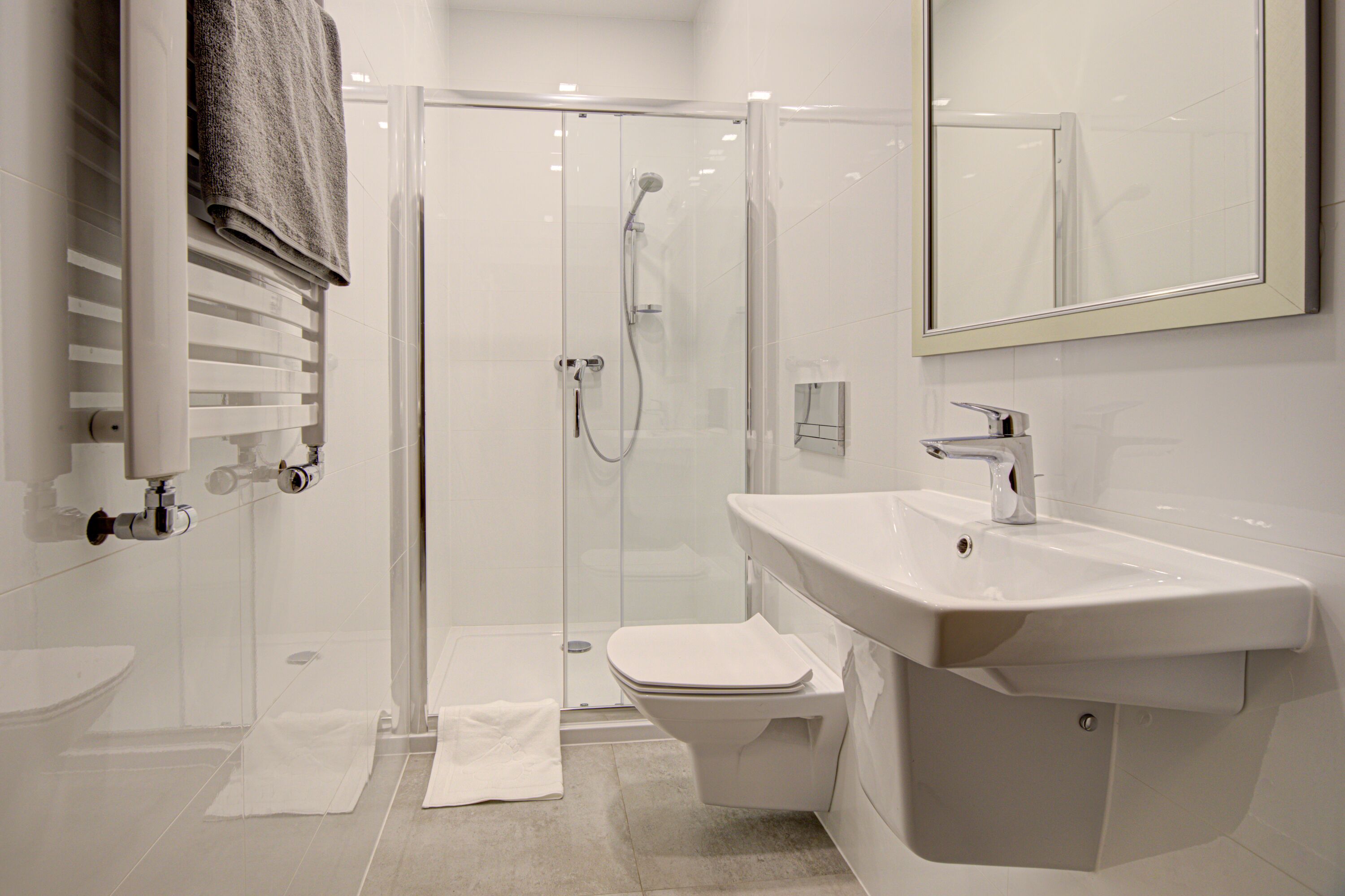 A modern bathroom with a glass-enclosed shower, a white sink, and a toilet.