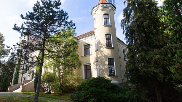 A building with a tower, large windows, and a staircase leading to the entrance.