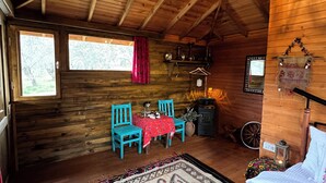 A cozy wooden cabin with a high ceiling, a dining area with a red tablecloth, turquoise chairs, and a patterned rug. - Yiva Kazdaglari (Edremit)